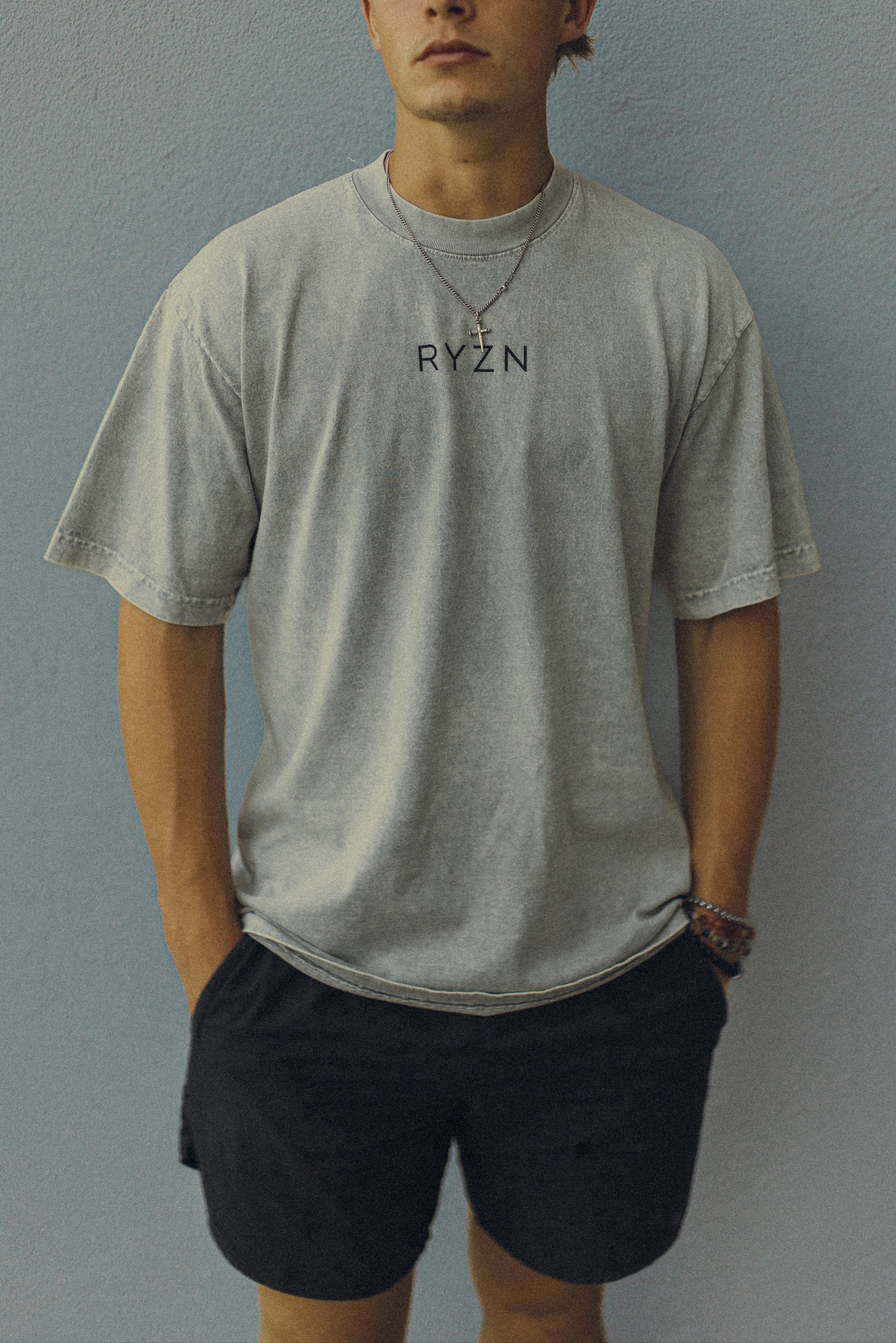Person wearing a gray t-shirt with 'RYZN' text against a plain background